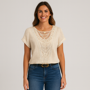 Woman wearing a beige lace top and blue jeans on a plain background