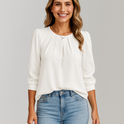 Woman wearing a white blouse and blue jeans against a gray background