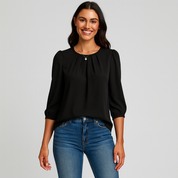 Woman wearing a black blouse and blue jeans on a gray background